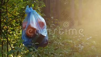一包塑料垃圾挂在树林里的树枝上，特写，自然污染的垃圾，阳光明媚，乱扔垃圾